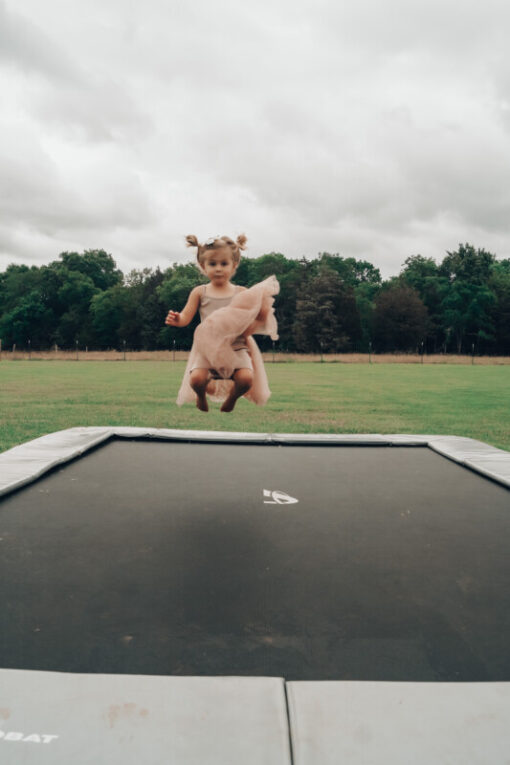 toddler jumping on gray inground trampoline