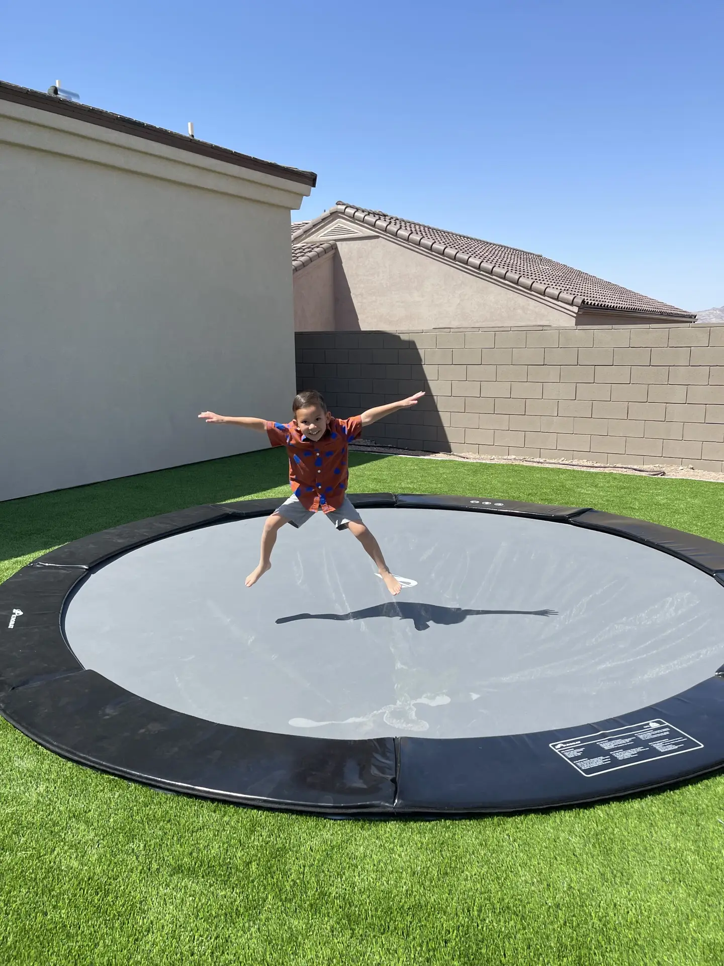 12ft Round Akrobat Primus Flat In-Ground Trampoline - Black (Black Pad with Grey Jump Mat) 3 child jumping on a black round inground trampoline