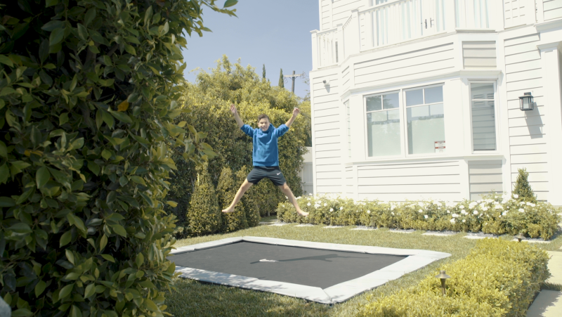 child jumping on a gray inground trampoline