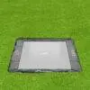 A square trampoline set on vibrant grass, perfect for jumping and enjoying outdoor activities.