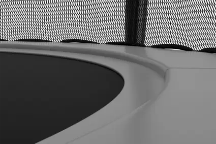 A black and white depiction of a trampoline, focusing on its frame and surface, creating a striking visual contrast.