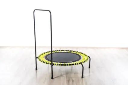 A trampoline featuring a sturdy black frame and a vibrant yellow seat, ready for fun and exercise.
