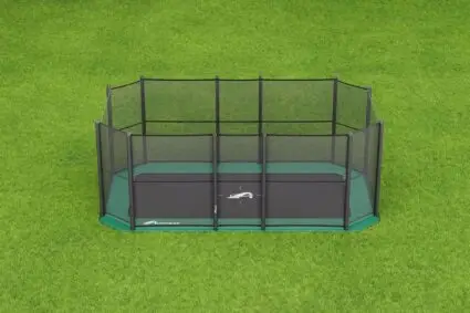 A small green trampoline placed on a grassy area, inviting outdoor fun and exercise.