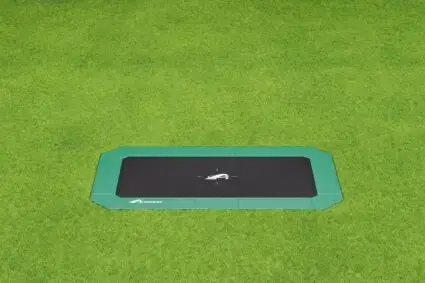 A black and green square trampoline set on a grassy area, inviting for outdoor fun and exercise.