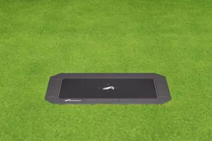 A black trampoline located on a lush green field, ideal for outdoor fun and exercise.