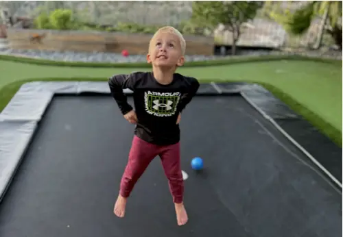 A young boy joyfully jumps on a trampoline, capturing the essence of play and childhood excitement.
