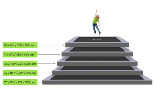 An individual leaps on a trampoline, highlighting its size and the energetic atmosphere around them.