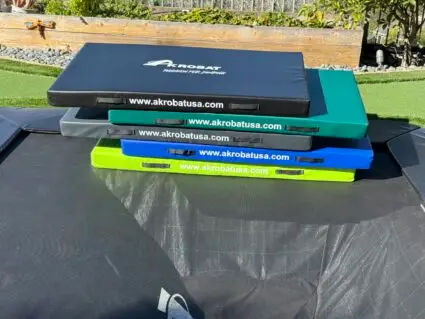 AkrobatUSA Landing Mat 9 A trampoline featuring four distinct colored pads, showcasing a vibrant and playful design for recreational use.