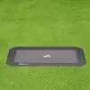 A black rectangular tray placed on a vibrant green field, contrasting the dark surface with the lush grass beneath.