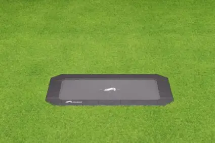 A black rectangular tray placed on a vibrant green field, contrasting the dark surface with the lush grass beneath.